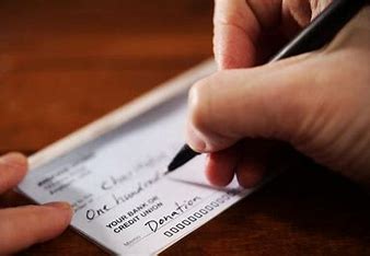 A hand holding a pen writing a check